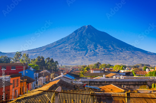 Beautiful outdoor view of rooftops of the building in Antigua city with agua volcano mountain behind in a beautiful sunny day and blue sky