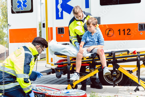 Emergency doctors caring for accident victim boy sitting on stretcher photo