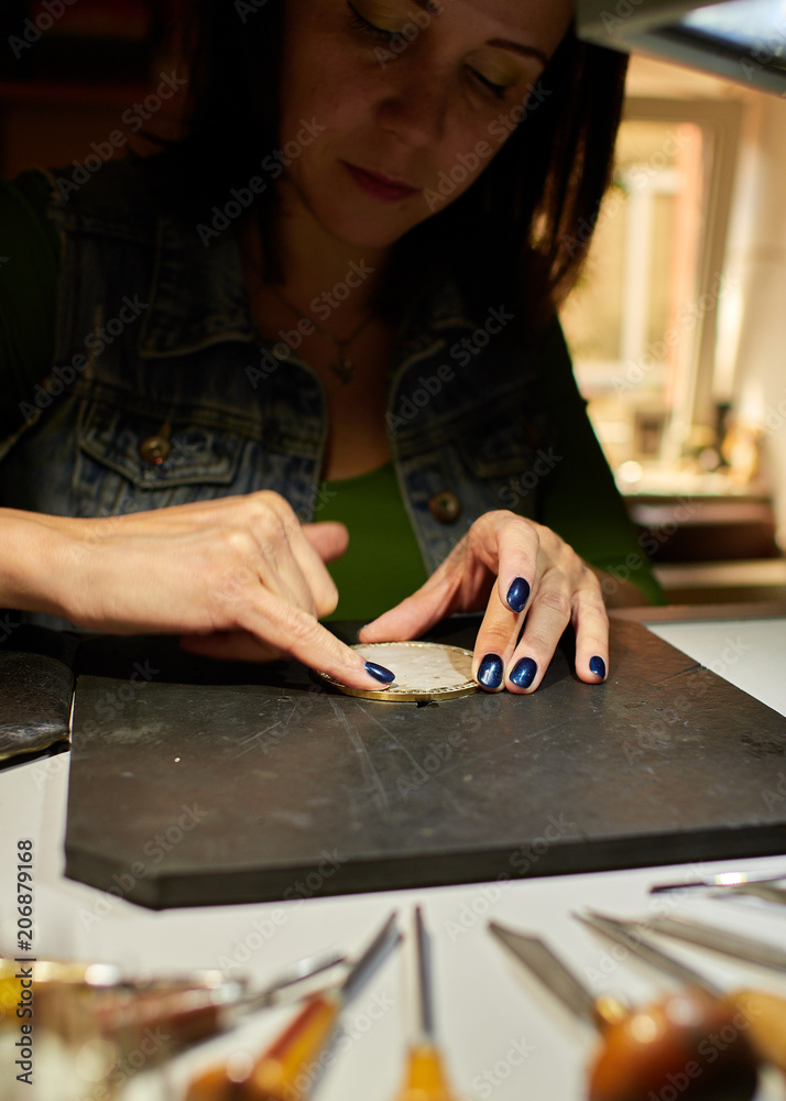 Fototapeta premium the engraver applies paste to the medal.