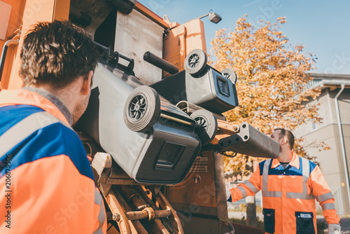 Fotografie Garbage removal Worker emptying dustbin into waste vehicle
