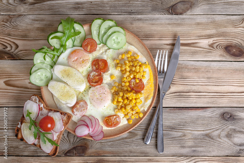 Breakfast. Fried eggs with cherry tomatoes, mozzarella cheese, fresh vegetables and homemade sandwiches. Healthy breakfast concept.