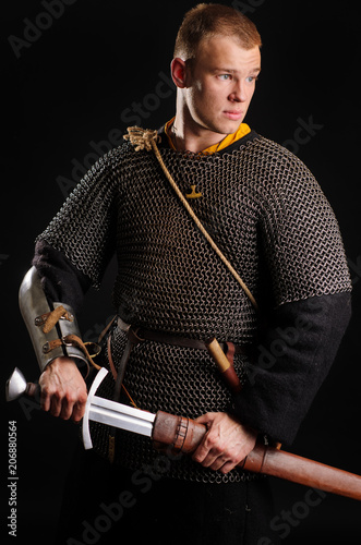 A soldier in a chain of letters stands with a sword in his hands
