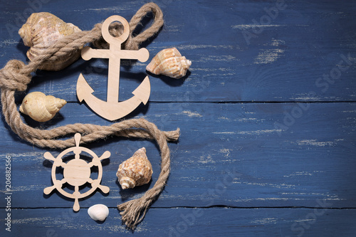 Marine attributes. Rope, frame, wooden anchor and steering wheel on a blue wooden background. Top view