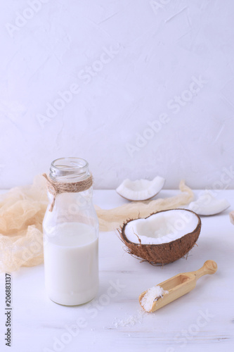 Organic coconut milk with hafl of fresh coconut on the background