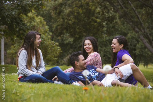 four friends lying on the grass laughing