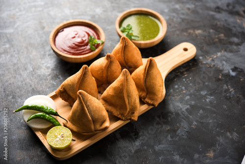 Samosa snack served with tomato ketchup and mint chutney photo