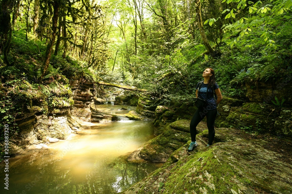 Young woman in the forest near the mountain river