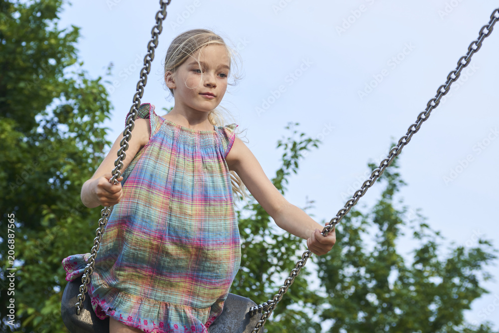 Little child blond girl having fun on a swing outdoor. Summer playground. Girl swinging high. Young child on swing outdoors
Little child blond girl having fun on a swing outdoor. Summer playground. Girl swinging high. Young child on swing outdoors