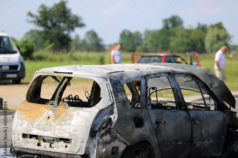 Spalony samochód osobowy na ulicy i poszkodowani ludzie. - obrazy, fototapety, plakaty 