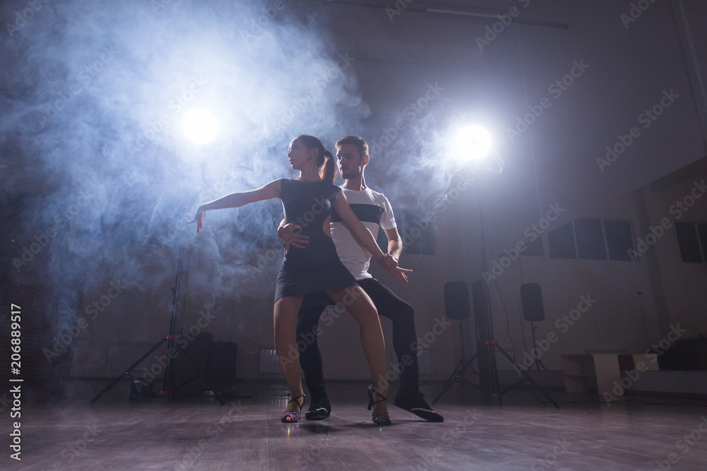 Skillful dancers performing in the dark room under the concert light and smoke. Sensual couple performing an artistic and emotional contemporary dance