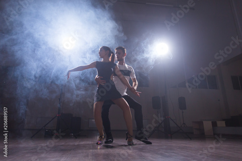 Skillful dancers performing in the dark room under the concert light and smoke. Sensual couple performing an artistic and emotional contemporary dance