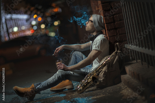 A street musician smokes and drinks coffee.