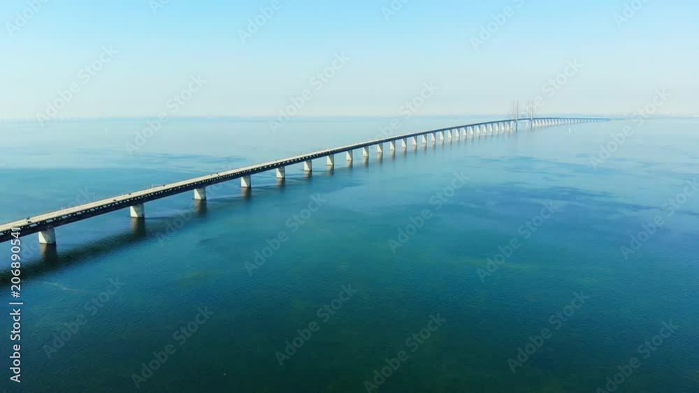 Aerial view of modern Oresund Bridge between Denmark and Sweden (Copenhagen and Malmo), clear blue sky, seascape of Baltic Sea with diagonal composition of very long sea bridge disappearing on horizon Aerial view of modern Oresund Bridge between Denmark and Sweden (Copenhagen and Malmo), clear blue sky, seascape of Baltic Sea with diagonal composition of very long sea bridge disappearing on horizon