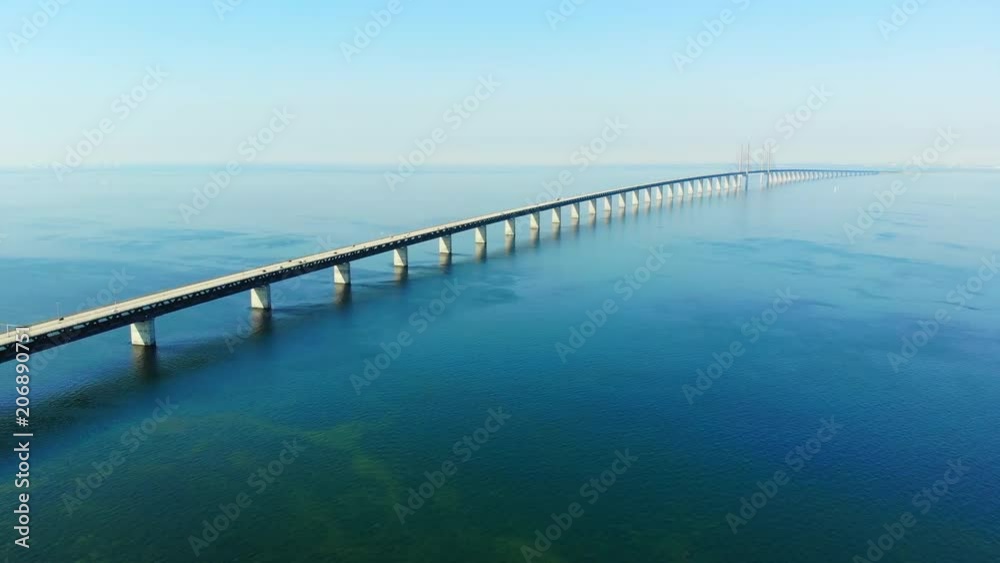 Aerial view of modern Oresund Bridge between Denmark and Sweden (Copenhagen and Malmo), clear blue sky, seascape of Baltic Sea with diagonal composition of very long sea bridge disappearing on horizon Aerial view of modern Oresund Bridge between Denmark and Sweden (Copenhagen and Malmo), clear blue sky, seascape of Baltic Sea with diagonal composition of very long sea bridge disappearing on horizon