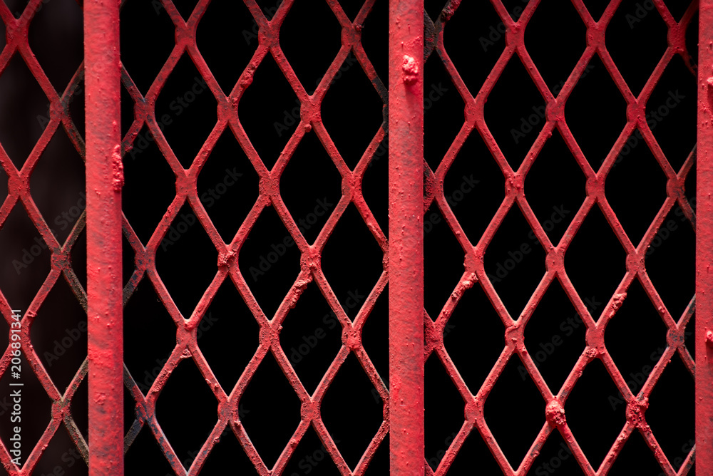 Obraz premium An abstract shot of fine red painted wire lattice on a barred window in Johannesburg inner city