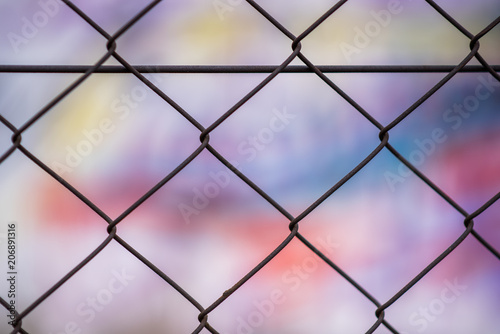 An abstract patterend shot of wire mesh fencing with blurred colorful graffiti in the background in Johannesburg inner city photo