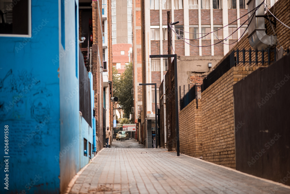 Fototapeta premium Aleja w Johannesburgu z budynkiem pomalowanym na niebiesko na pierwszym planie