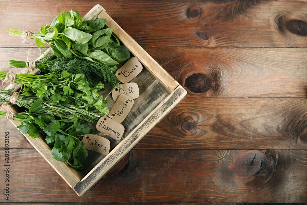 Different fresh herbs in box on brown wooden table Different fresh herbs in box on brown wooden table