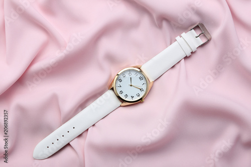 Wrist watch on pink satin background