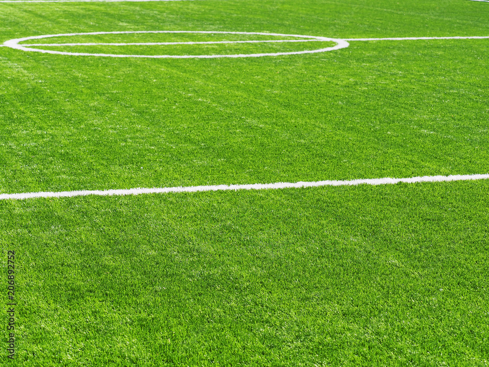 White stripe on the green soccer field from side view. Artificial turf on football field. Green synthetic grass on sport ground with white lines