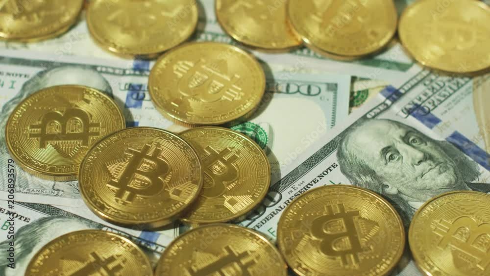 Arrangement of brightly shining bitcoins with symbols lying on heap of US dollar bills. 