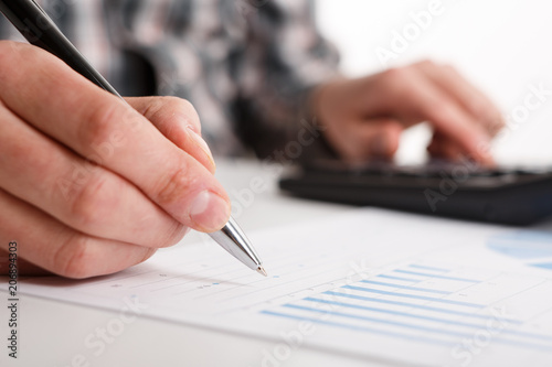 Business people use pen to point graphs to analyze company data