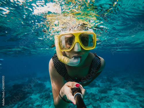 Lovely woman doing snorkeling at the gili islands in Indonesia. Wearing yellow glasses at the blue sea. Travel photography, lifestyle.