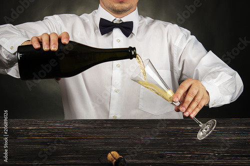 Cropped image of bartender pouring champagne into glass at bar counter photo