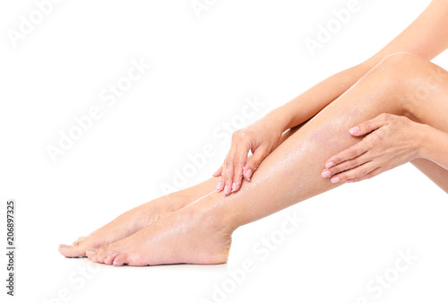 Young woman applying body scrub on leg against white background © New Africa