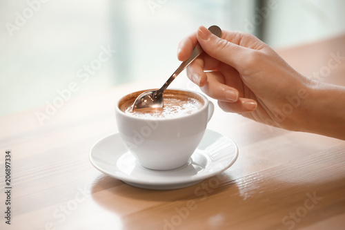 Woman with cup of aromatic coffee at wooden table