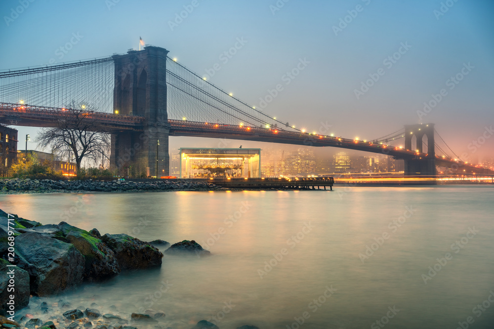 Brooklyn bridge and Manhattan at foggy evening, New York City