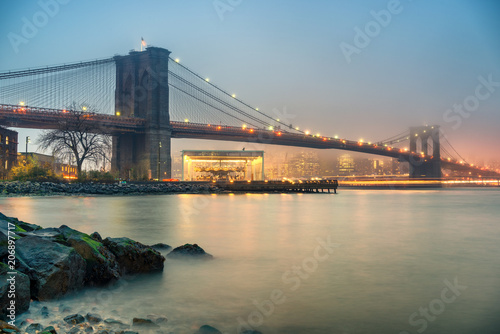 Brooklyn bridge and Manhattan at foggy evening  New York City