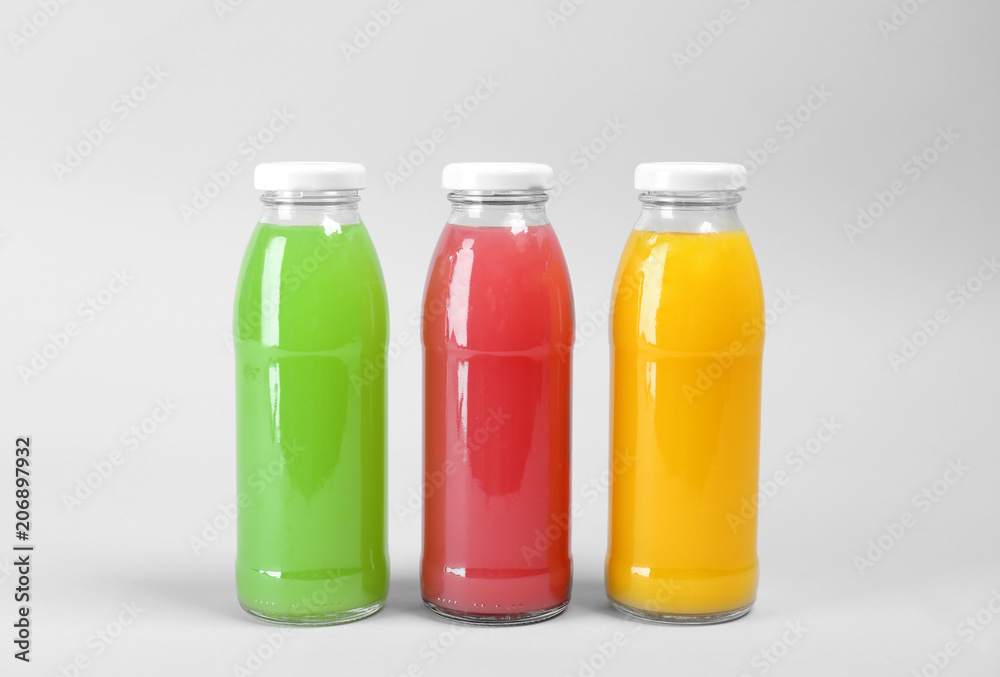 Bottles with delicious colorful juices on light background Bottles with delicious colorful juices on light background