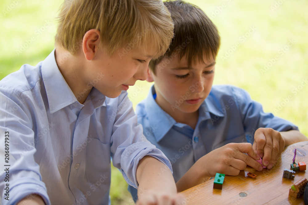 Two young brothers play together with blocks, outdoor Two young brothers play together with blocks, outdoor