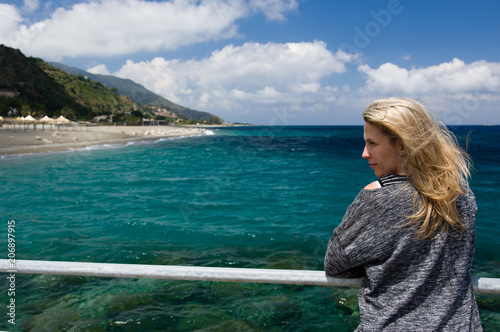Blonde woman outdoor, azure blue sea background, beach and mountan