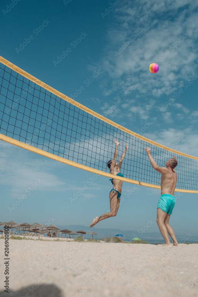 Summer vacation and travel on holiday in Miami. Sexy woman and muscular man with ball at net. Love and flirting of couple. Couple in love play volleyball on sunny beach. Sport activity and health