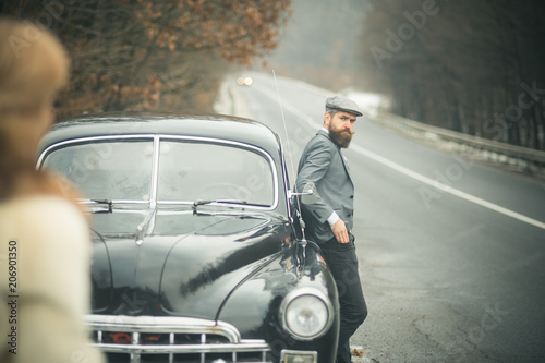 nostalgia concept. nostalgia and retro car at bearded man and woman in coat. © Volodymyr