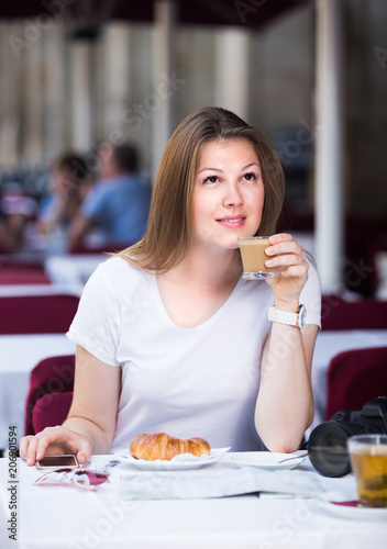 Young woman tourist is drinking coffee