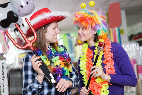 Two smiling young female friends having fun in festival outfits store