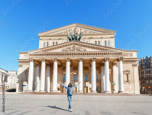 Rear view of a woman with a backpack admiring the majestic architecture and view of the Bolshoi Theater, tourism in Moscow and Russia concept