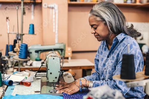 Mature woman using a sewing machine in her fabric workshop