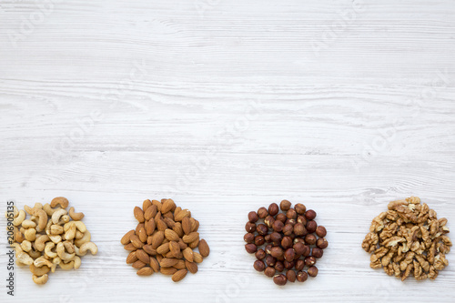 Assortment of nuts on white wooden background. Cashew, hazelnuts, walnuts, almonds. Top view. Copy space and text area.