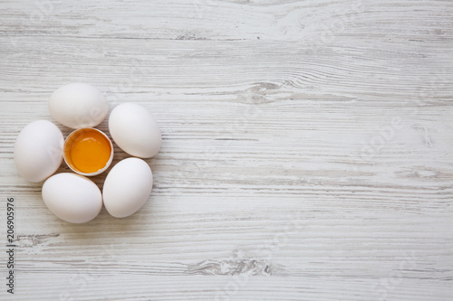 Chicken eggs on white wooden background, top view. Copy space.