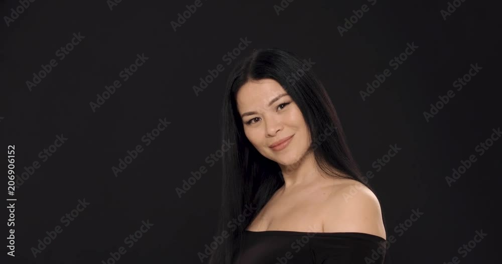 Side view image of attractive asian woman in black blouse posing on black background. Cared skin concept. Side view image of attractive asian woman in black blouse posing on black background. Cared skin concept.