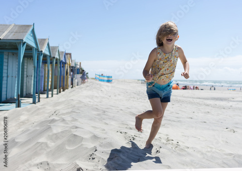Girl running with hair over face on the beach and beach huts