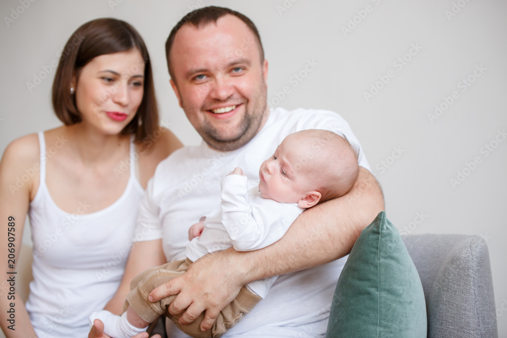 Photo of happy married couple with young child sitting on sofa Photo of happy married couple with young child sitting on sofa