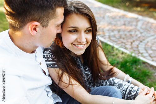 young, happy, loving couple, sitting together on the grass in the Park, and enjoying each other, advertising, and inserting text