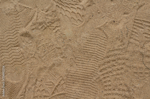 Yellow sand with foot marks photo texture. Shoe sole sand marks. Protecting feet on holiday. © Elya.Q