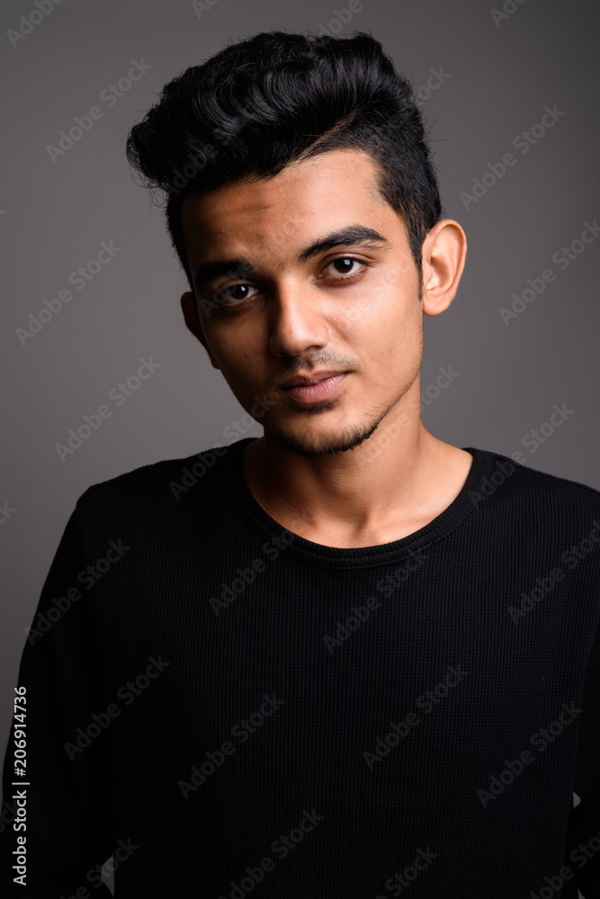Young Indian man against gray background