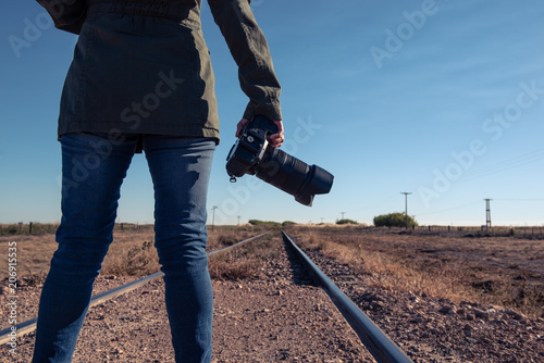 Woman holding an SLR camera from behind